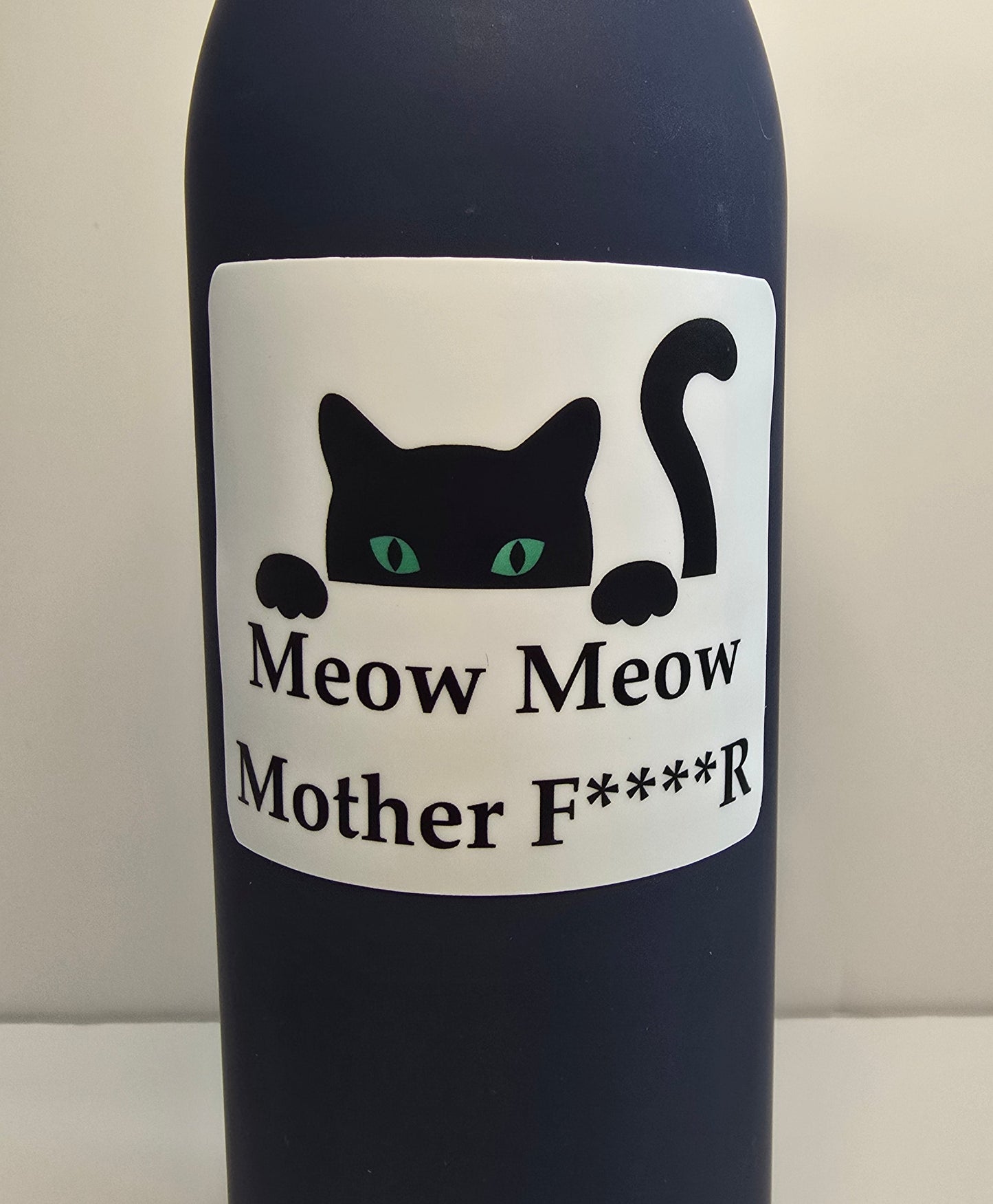 Bottle with a label featuring a black cat and text on a plain background