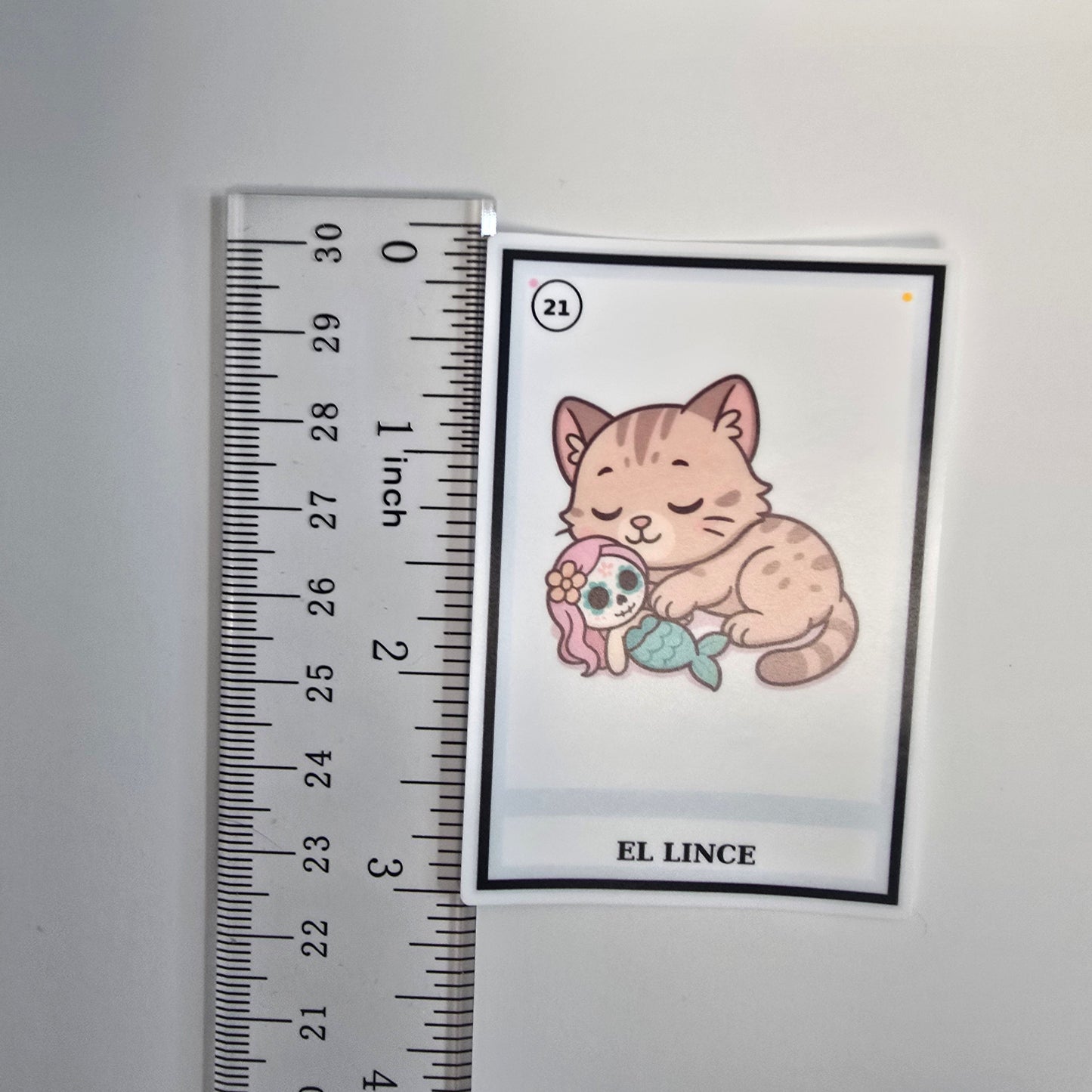 Cartoon cat and fish illustration on a card with a ruler for scale.