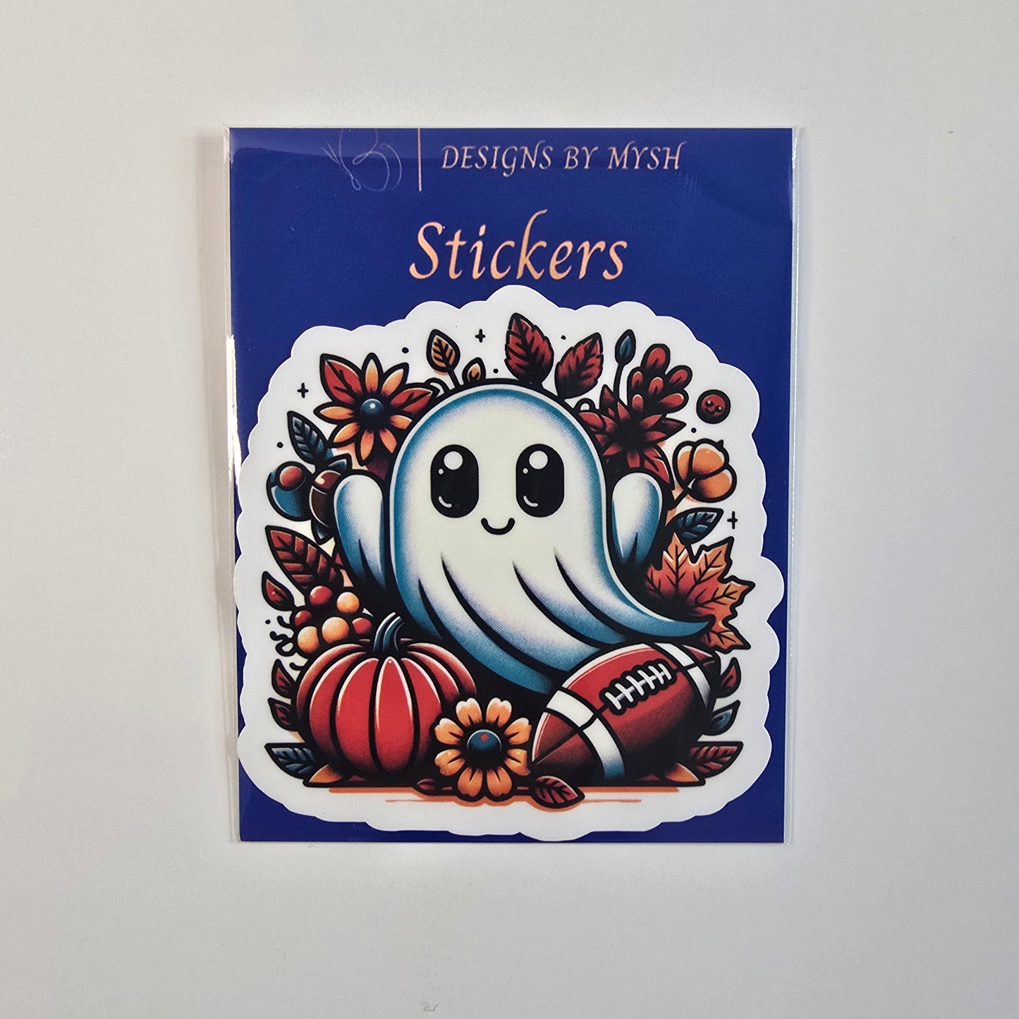 Die-cut vinyl sticker featuring a cute smiling ghost surrounded by pumpkins, fall leaves, flowers, and a football on a blue branded backing card.