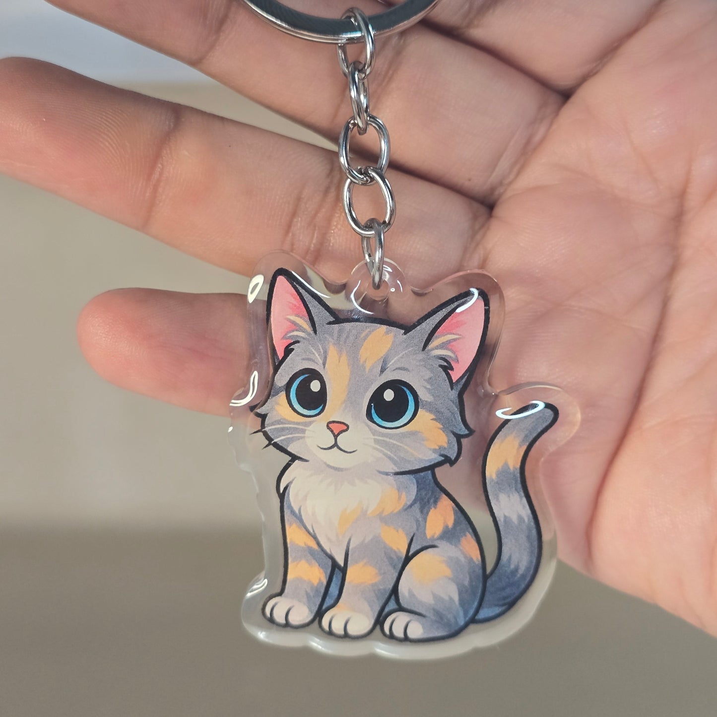 Keychain with a cat design held by a hand against a neutral background