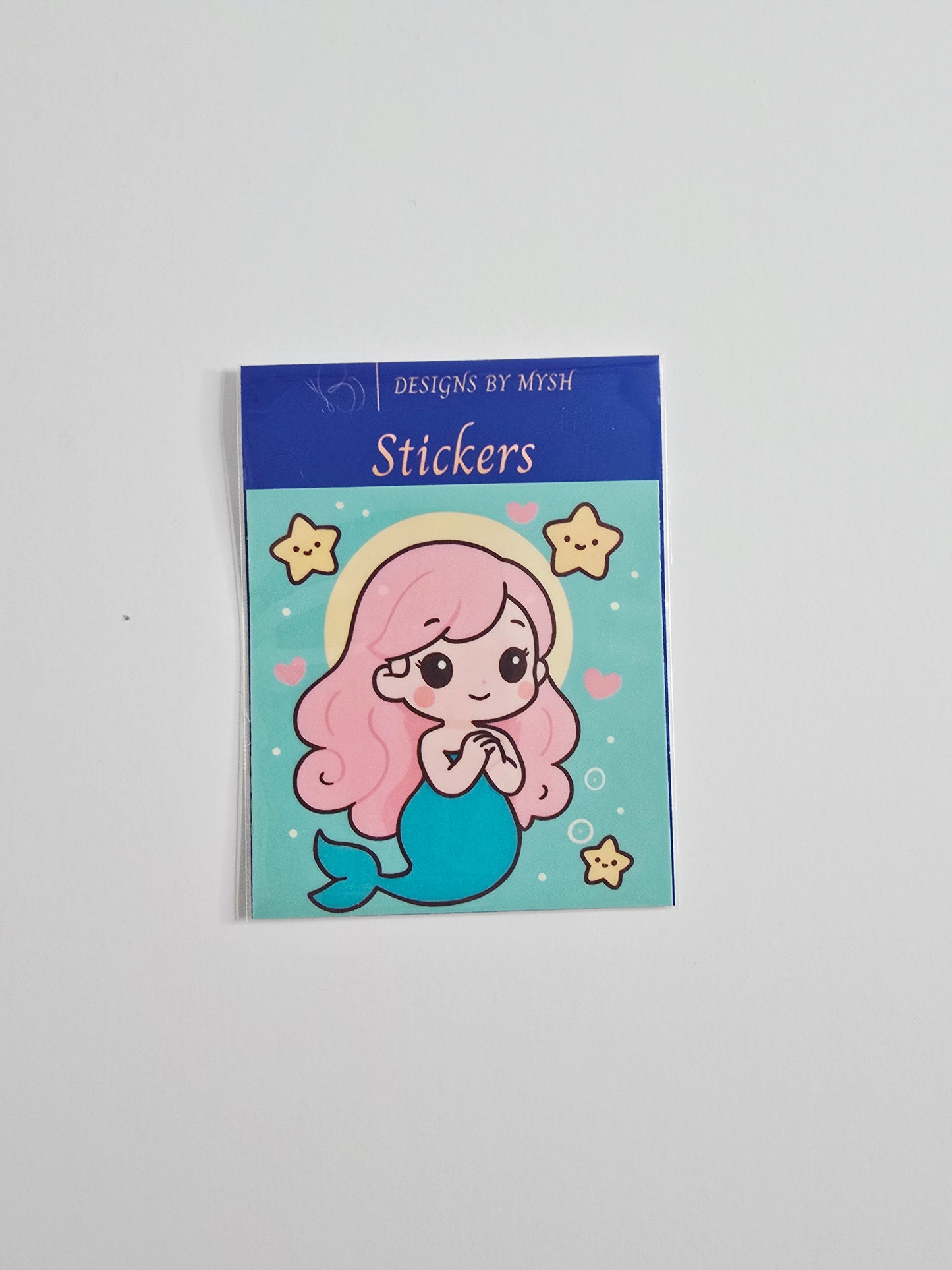 "Cartoon-style pink-haired mermaid surrounded by starfish and hearts on a turquoise background, printed on a 3-inch die-cut vinyl sticker with a glossy laminate overlay."