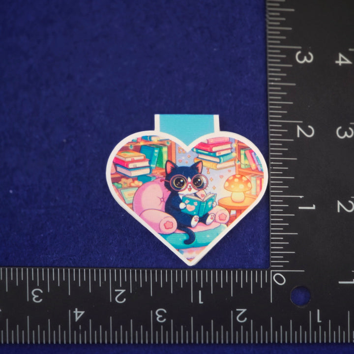 Heart-shaped sticker with a cat design on a blue background with a ruler for scale.