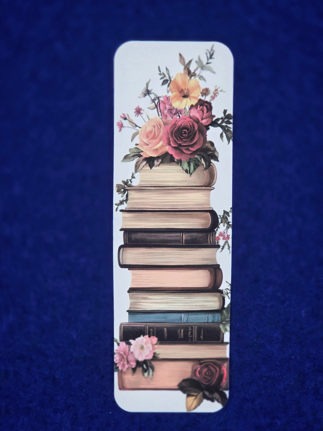 Bookmark with floral design on a stack of books against a blue background