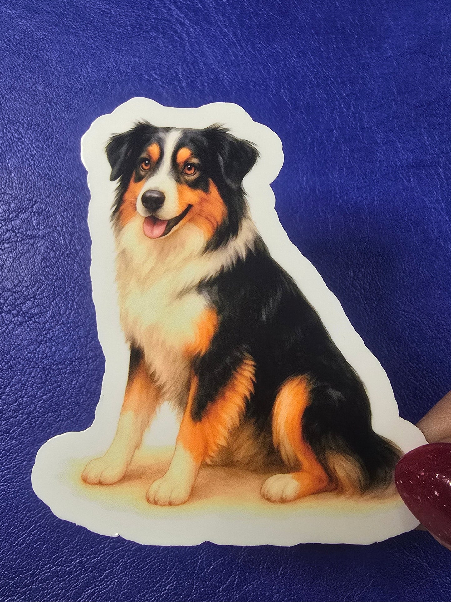 Sticker of a dog on a blue surface with a hand holding it.