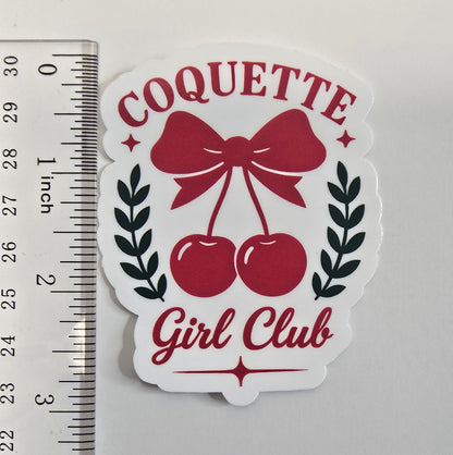 Coquette Girl Club sticker with red bow and cherries, surrounded by black laurel leaves on a white die-cut background.