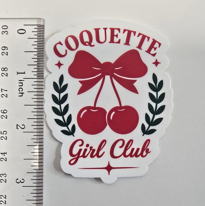 Coquette Girl Club sticker with red bow and cherries, surrounded by black laurel leaves on a white die-cut background.