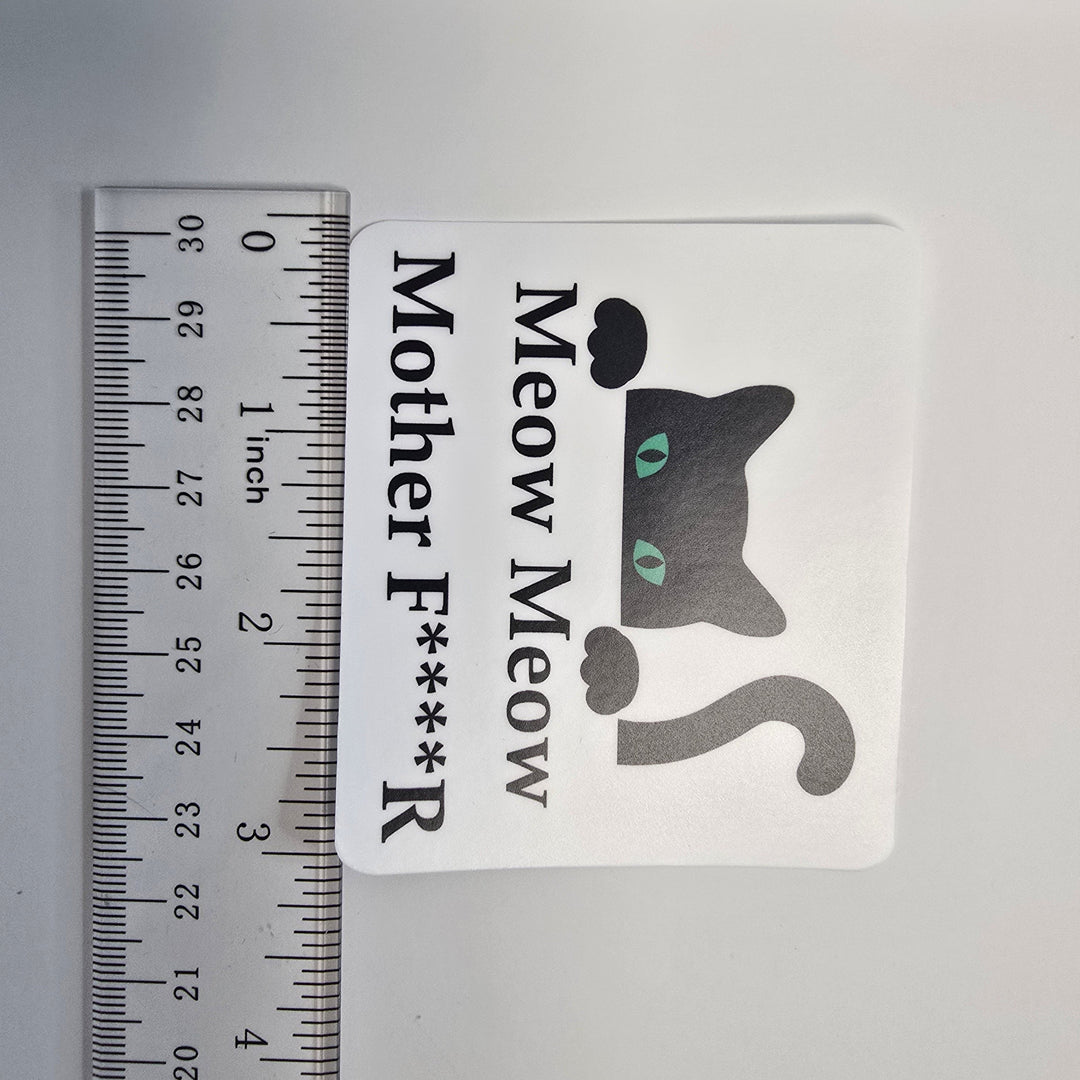 Sticker with a cat graphic and text next to a ruler for size reference on a gray background