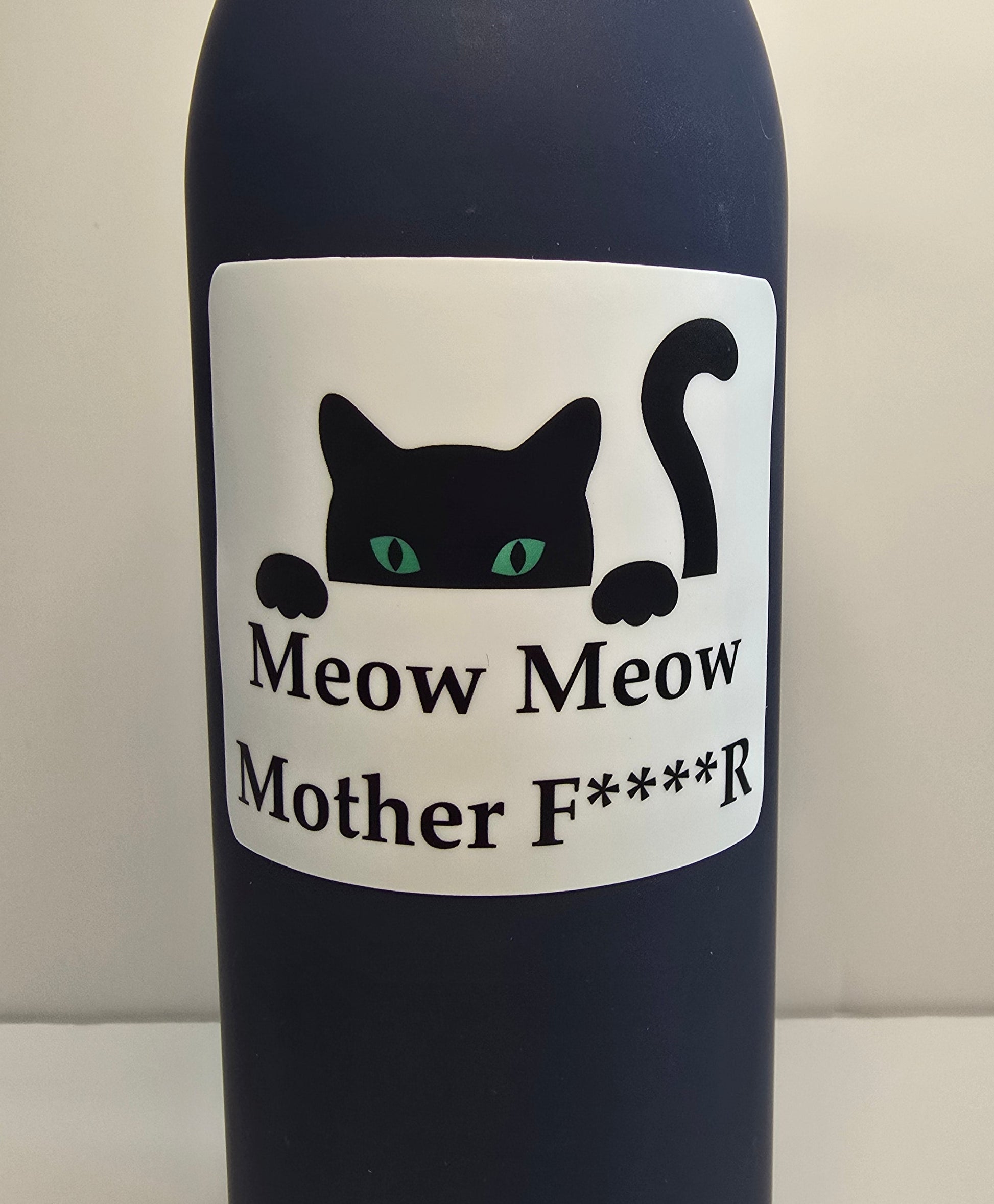 Bottle with a label featuring a black cat and text on a plain background