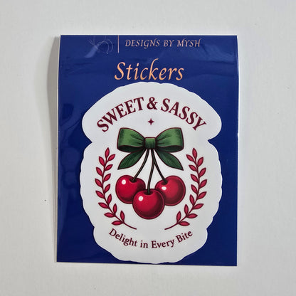 Retro-style cherry sticker with three red cherries tied in a green bow and labeled “Sweet & Sassy” with “Delight in Every Bite.”