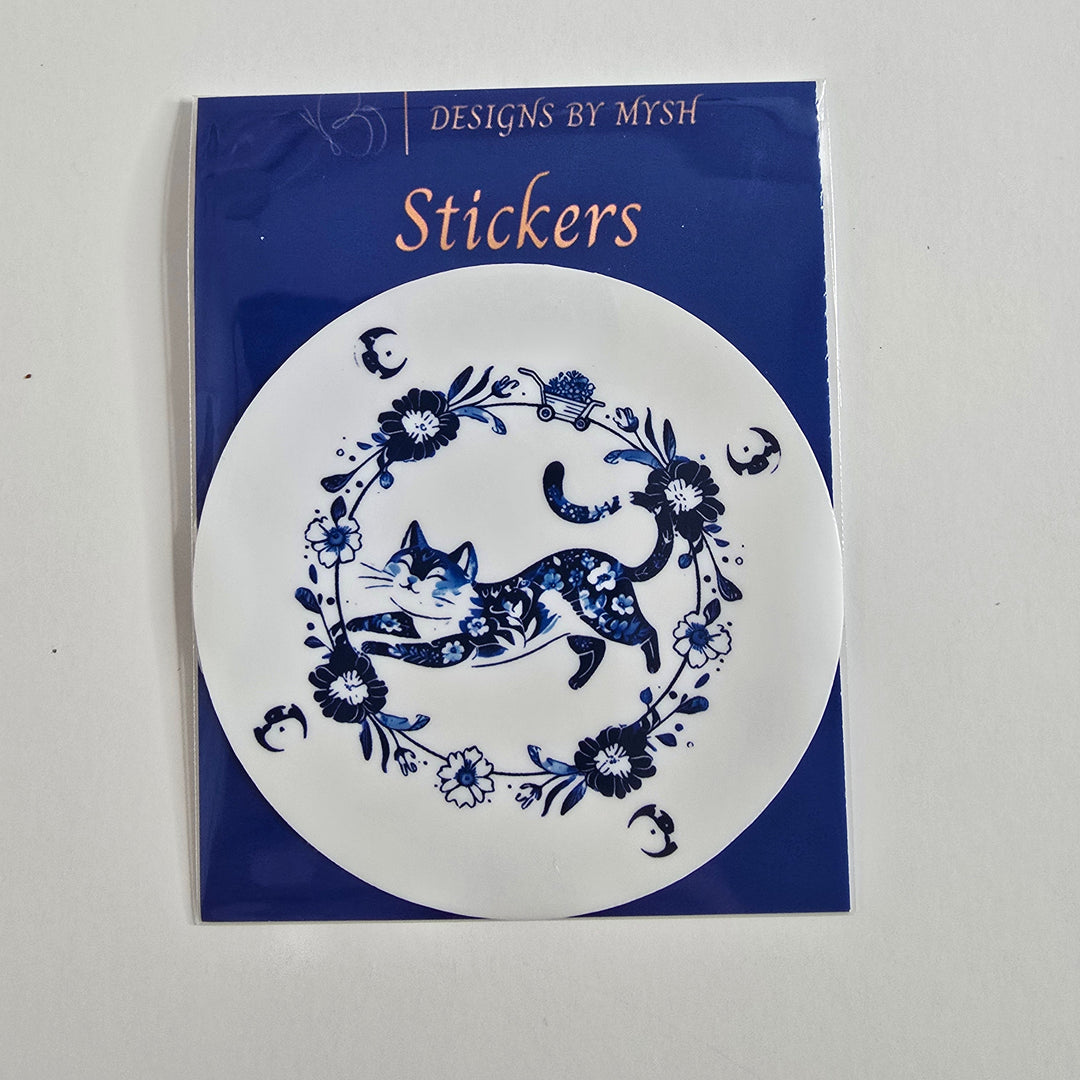 Sticker of a leaping blue floral cat encircled by matching flowers and crescent moons, inspired by Delftware porcelain design.