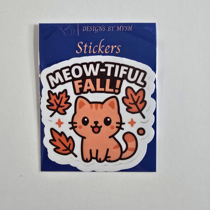 Sticker featuring an orange cartoon cat with text “Meow-tiful Fall!” surrounded by falling autumn leaves.