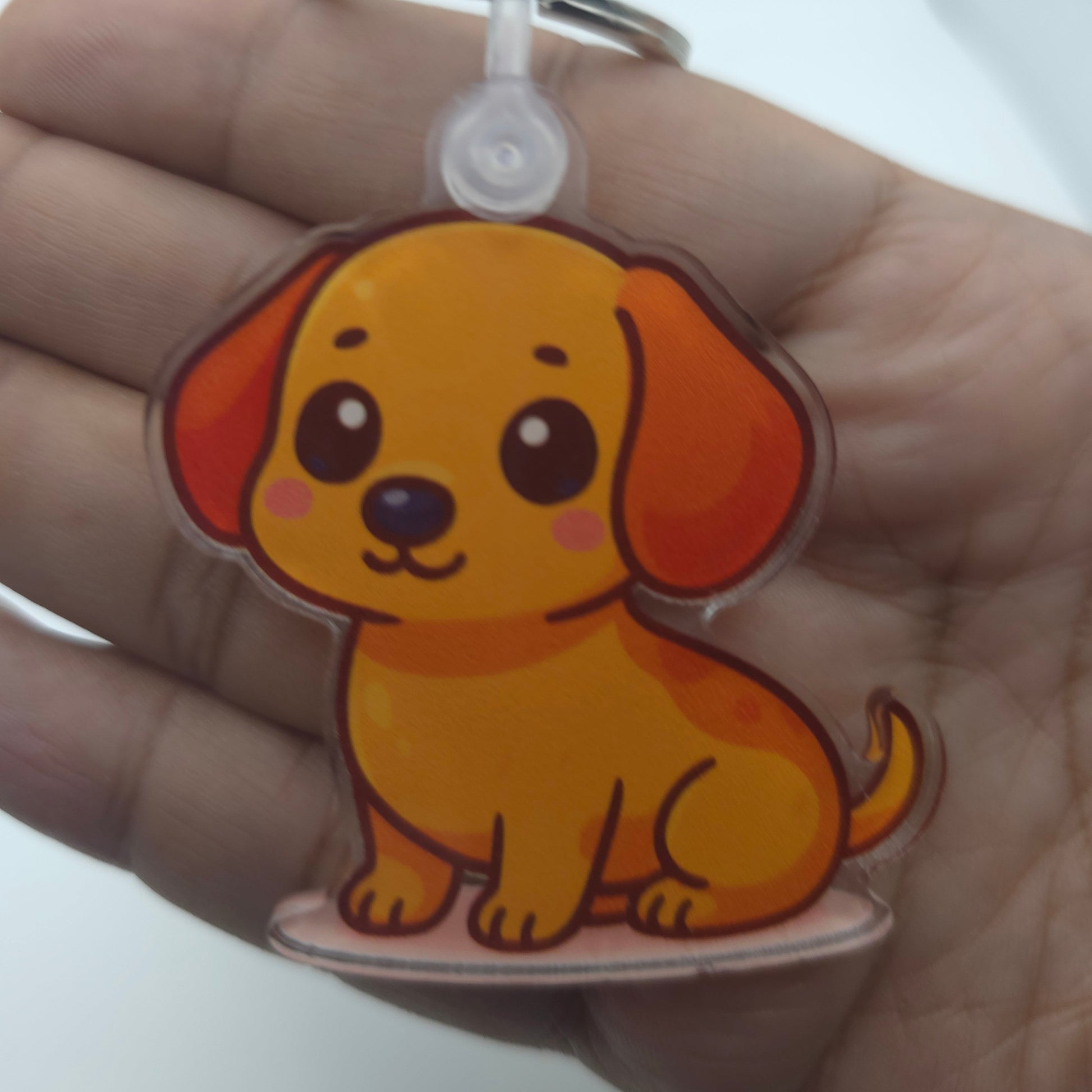 Cartoon dog keychain held in a hand against a white background