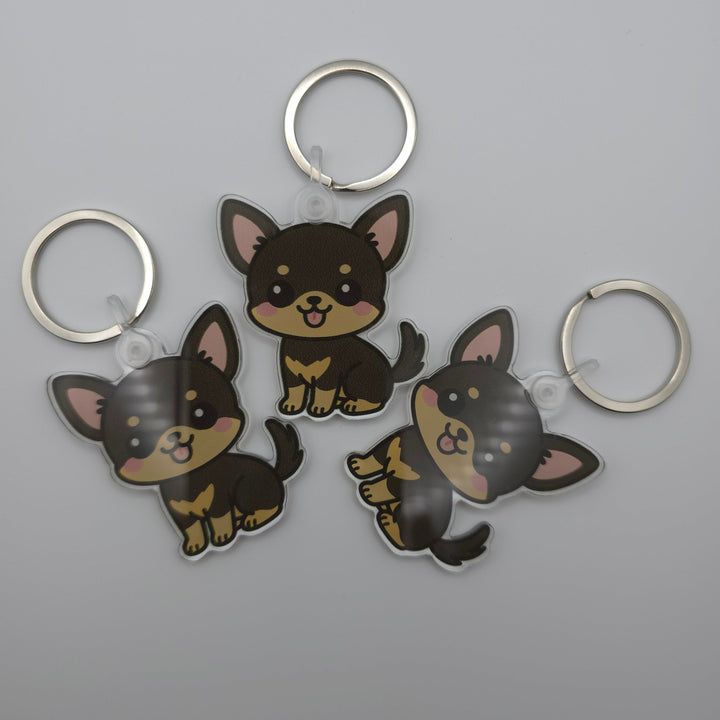 Three dog-shaped keychains on a gray background