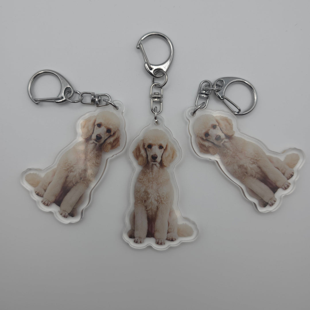 Three dog-shaped keychains with a clear background