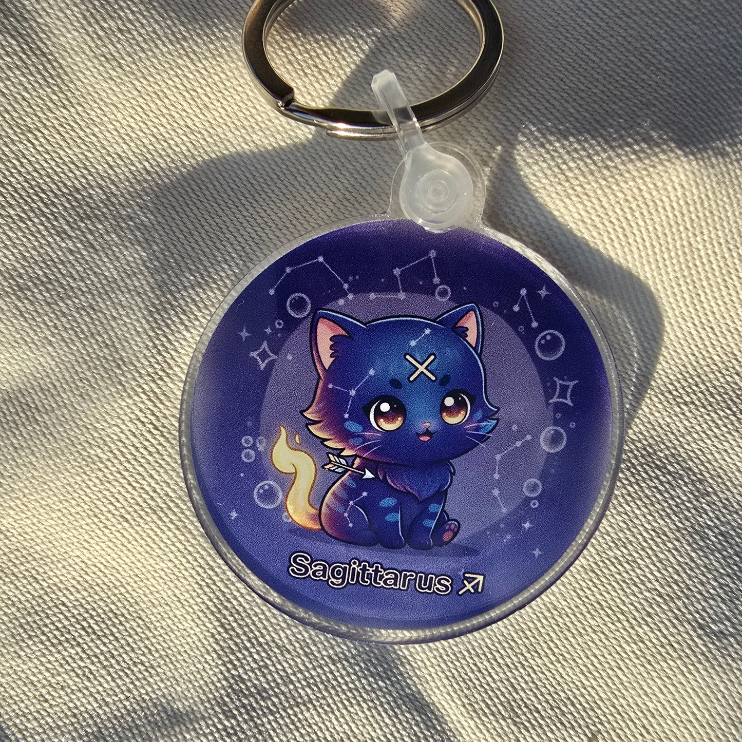 Keychain with a blue cat design on a textured beige surface