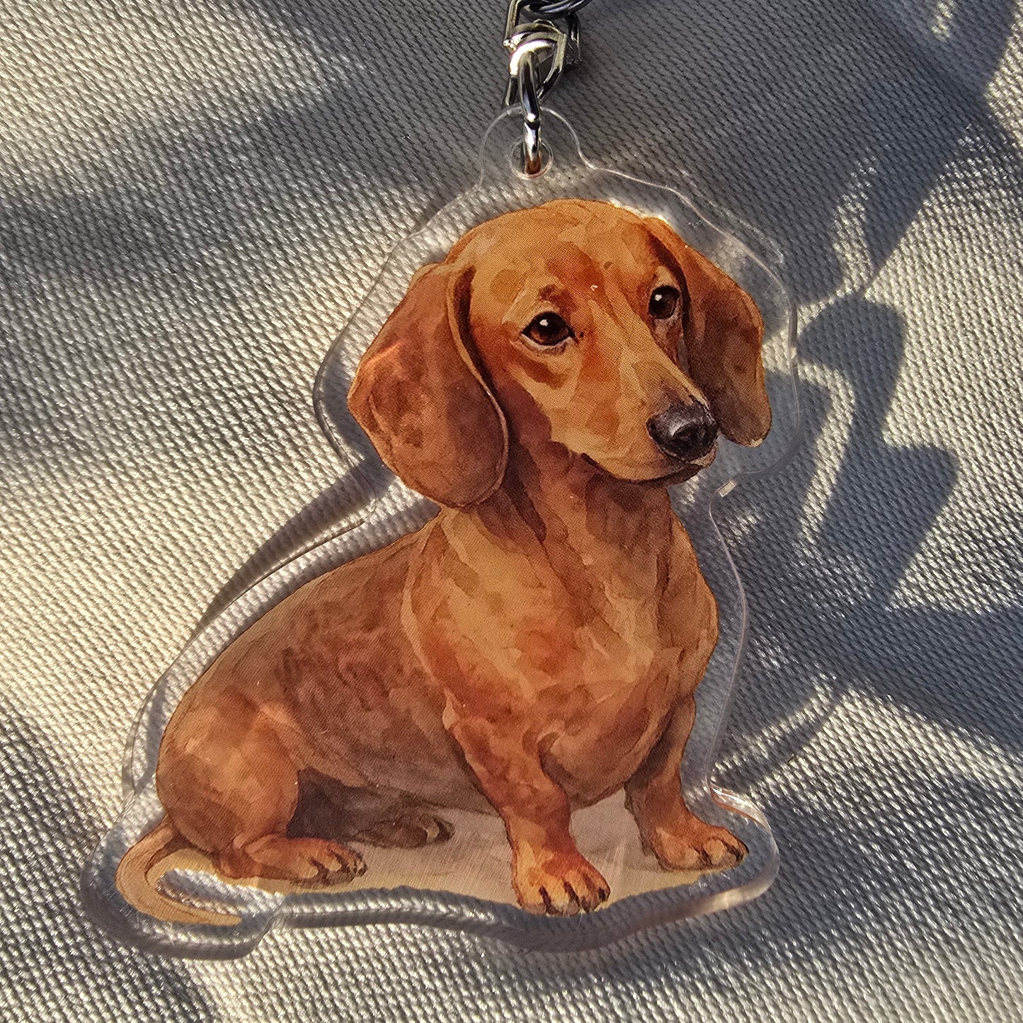 Red dachshund acrylic keychain in watercolor style with silver lobster clasp on canvas background