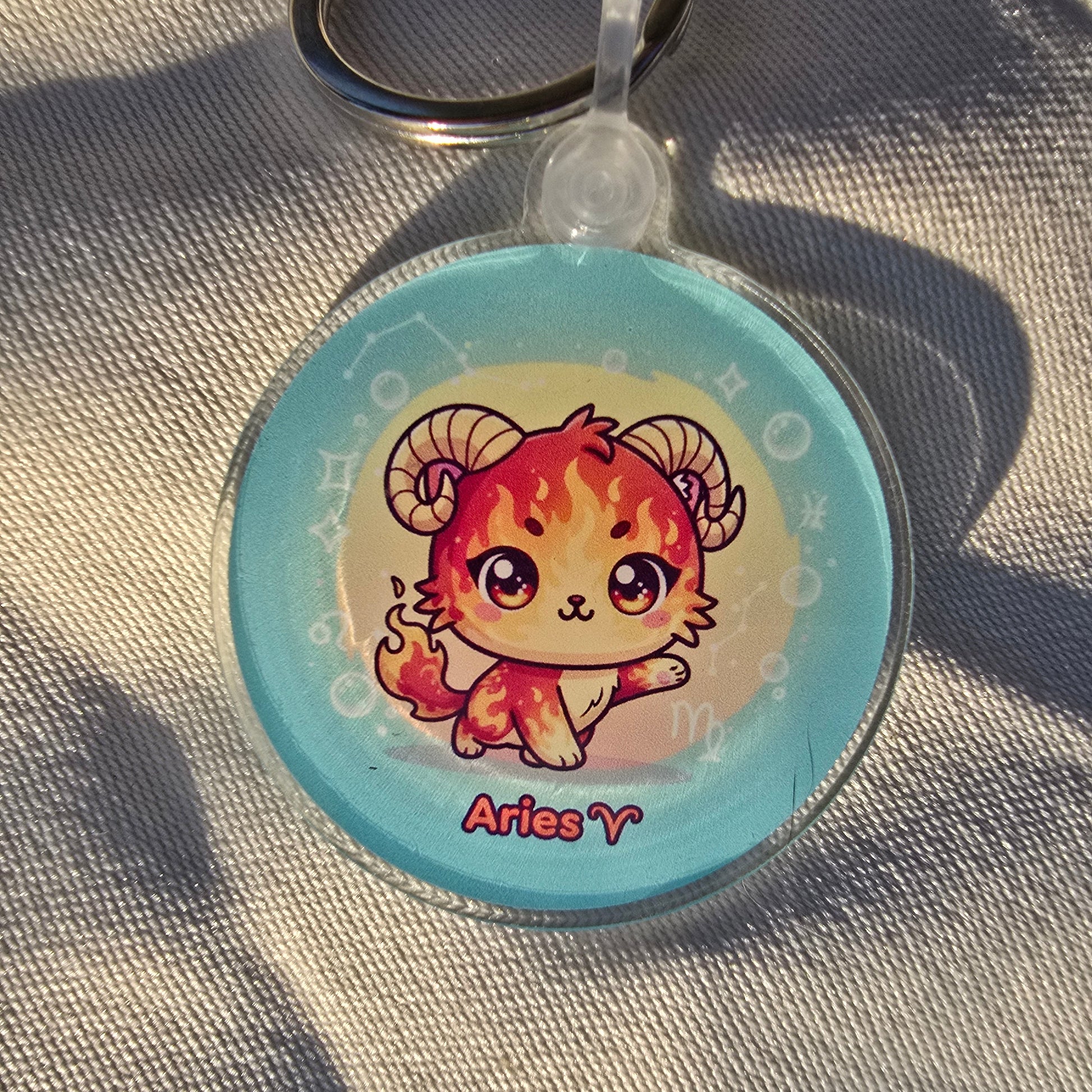 Keychain with Aries zodiac sign design on a textured fabric background