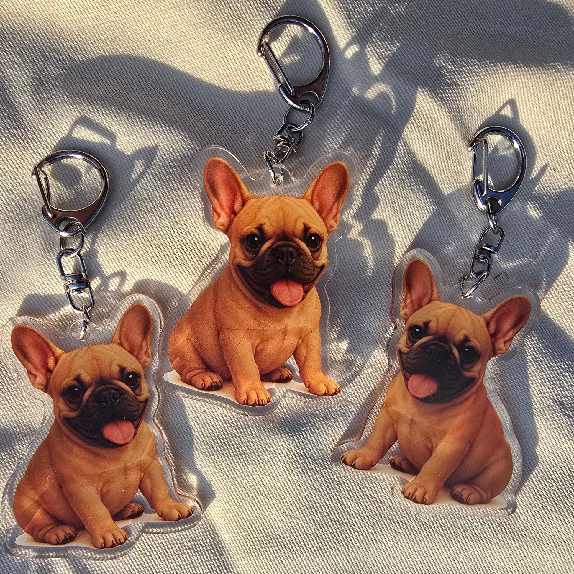 Three fawn French Bulldog acrylic keychains with smiling dog illustration and silver lobster clasps
