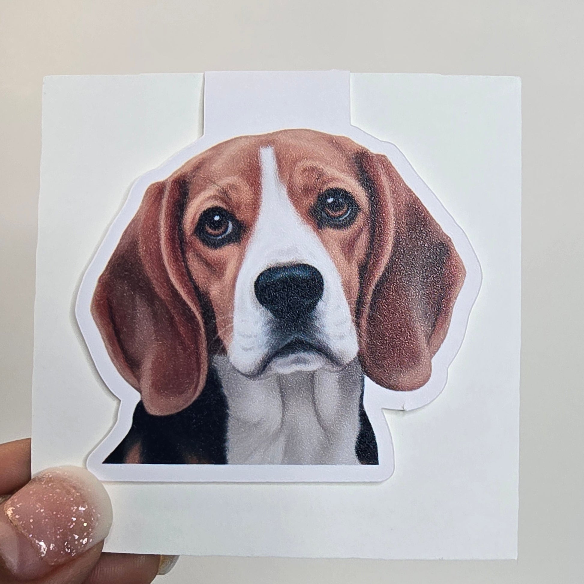 Hand holding a paper cutout of a dog's face with a grid pattern in the background