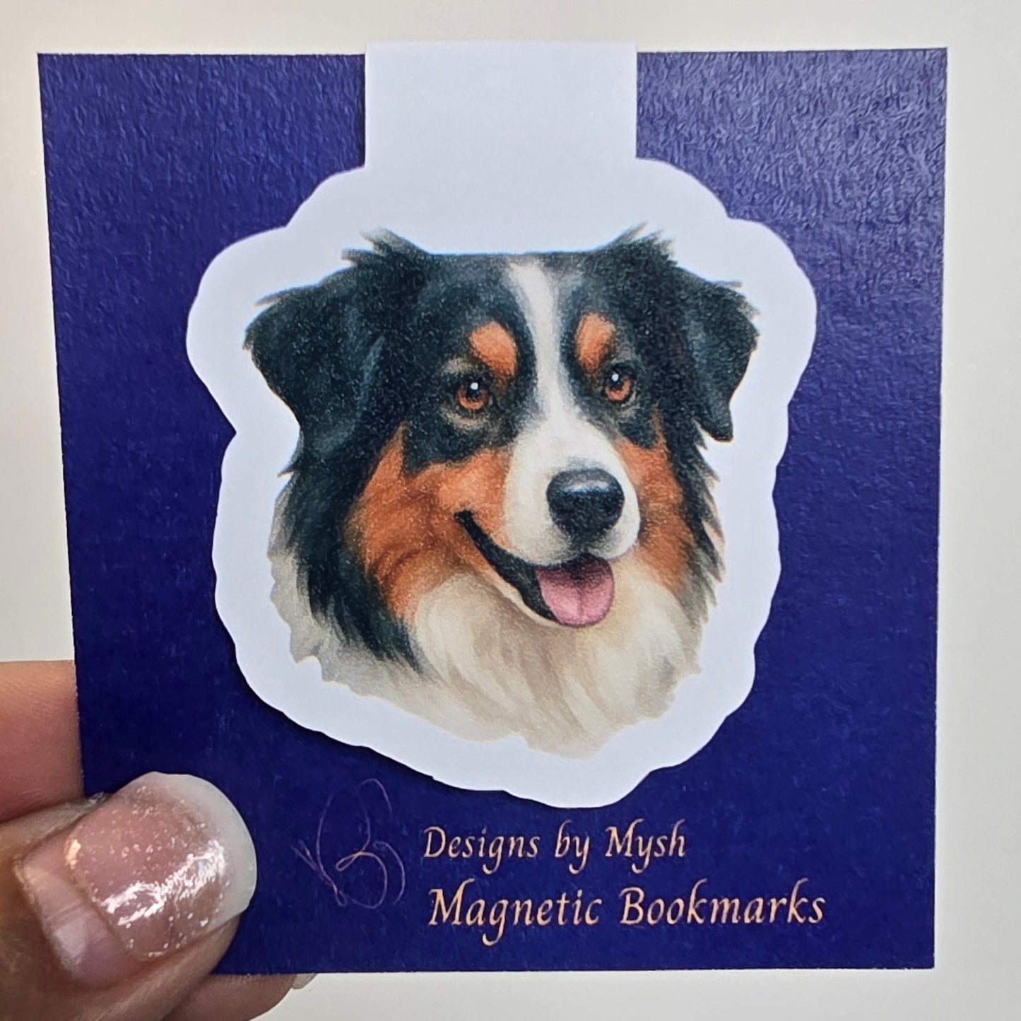 Magnetic bookmark with dog design held by a hand against a white background