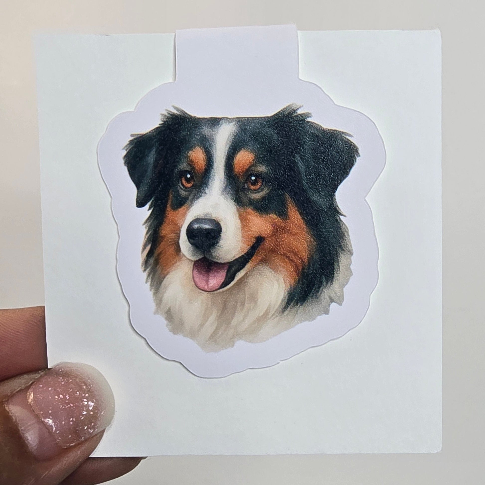 Hand holding a sticker of a dog's face on a white background
