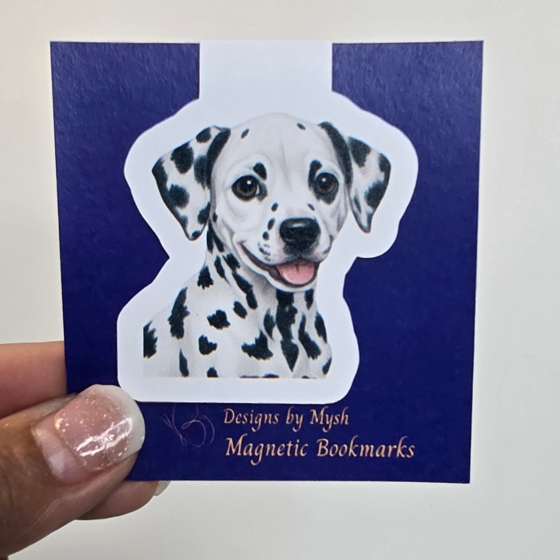 Hand holding a blue book with a dalmatian dog design on a white background
