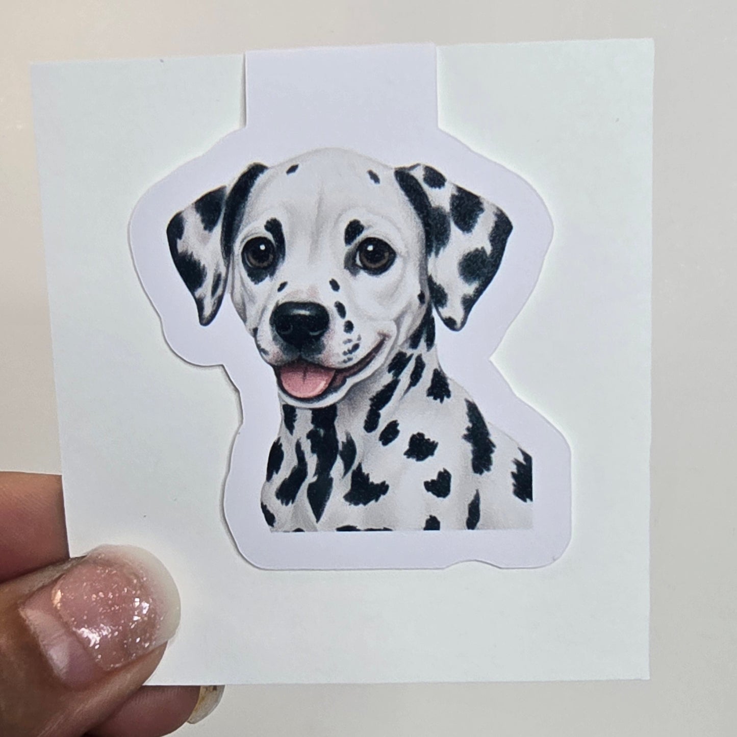 Sticker of a Dalmatian dog held by a hand against a white background
