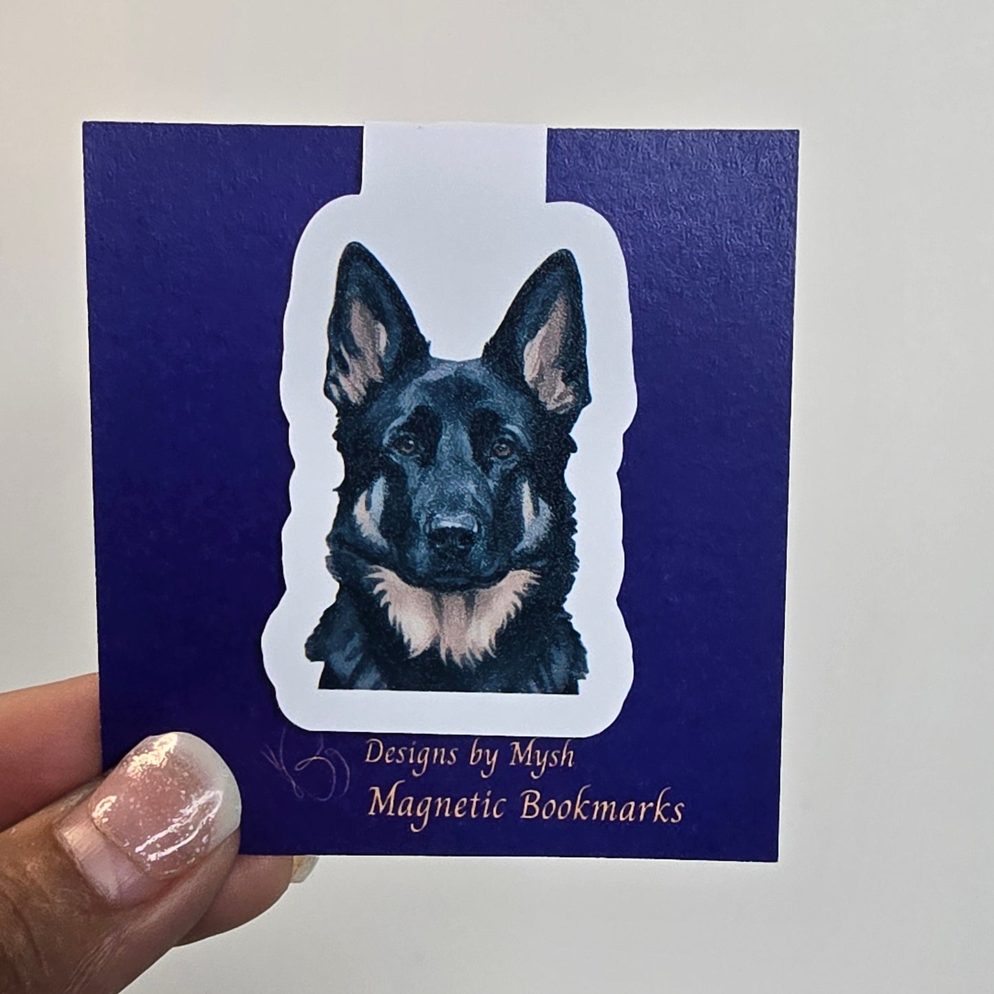 Hand holding a blue bookmark with a dog illustration and text on a white background