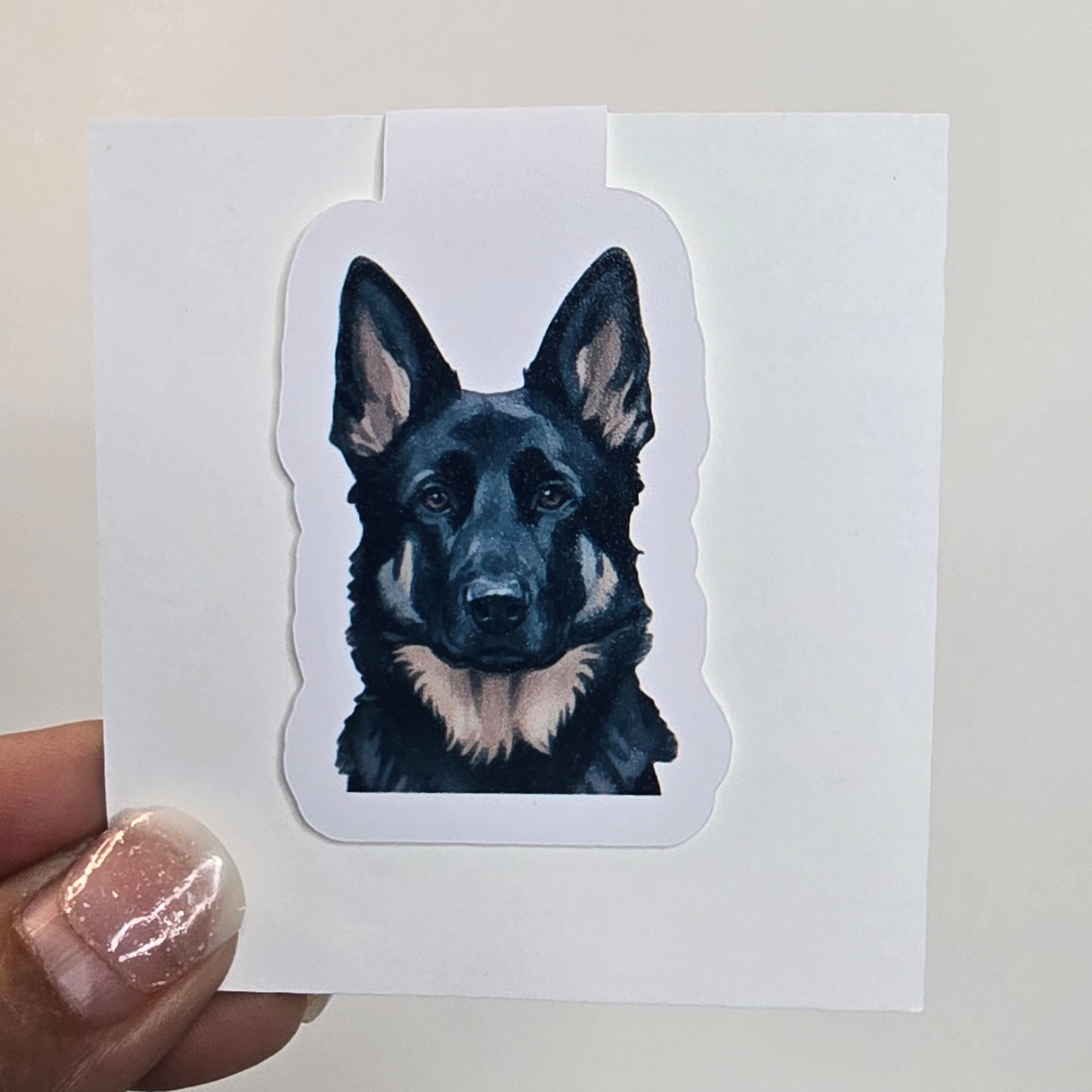 Sticker of a dog's face held over a white card with a grid pattern on the side.
