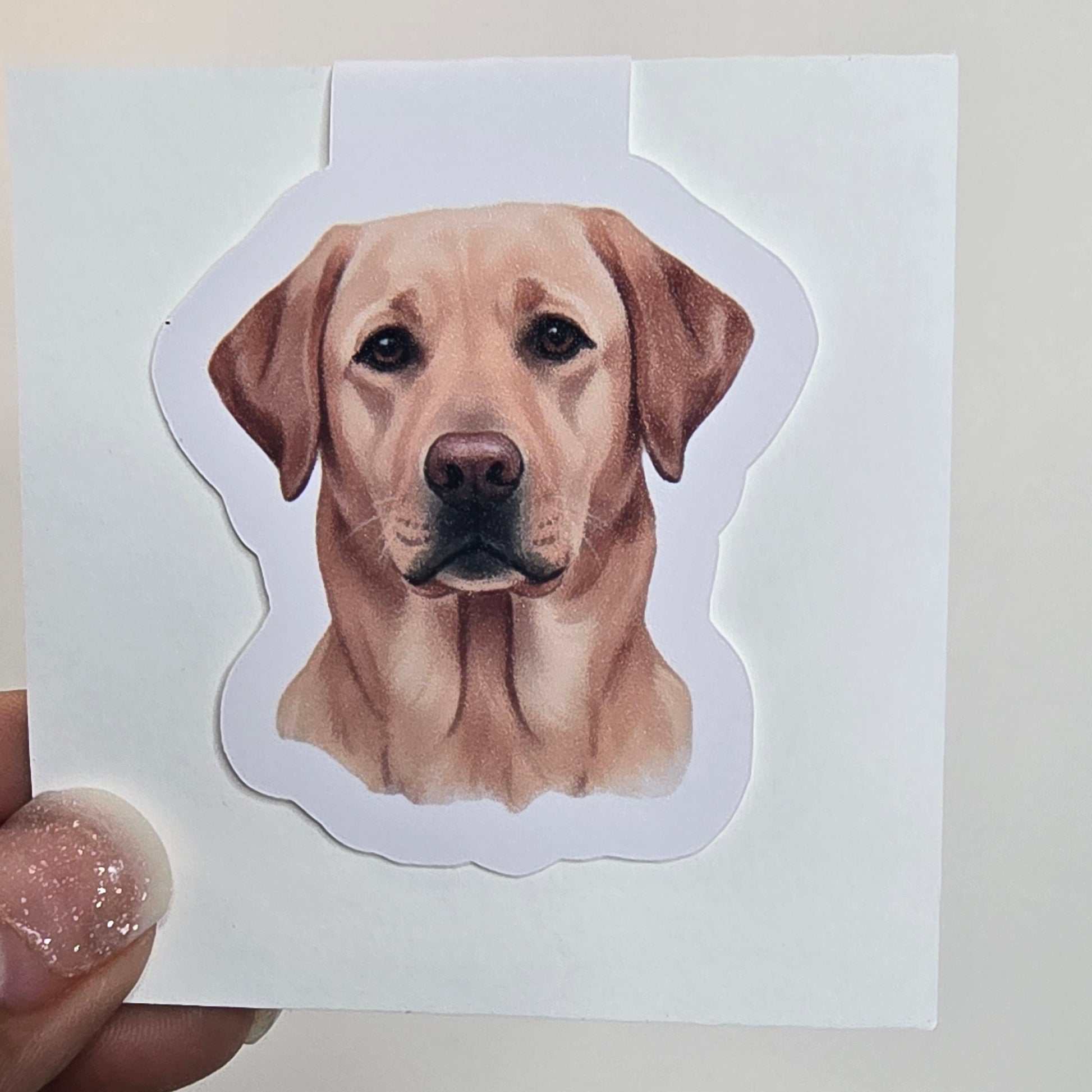 Dog-shaped sticker held over a white card with a grid pattern on the side.