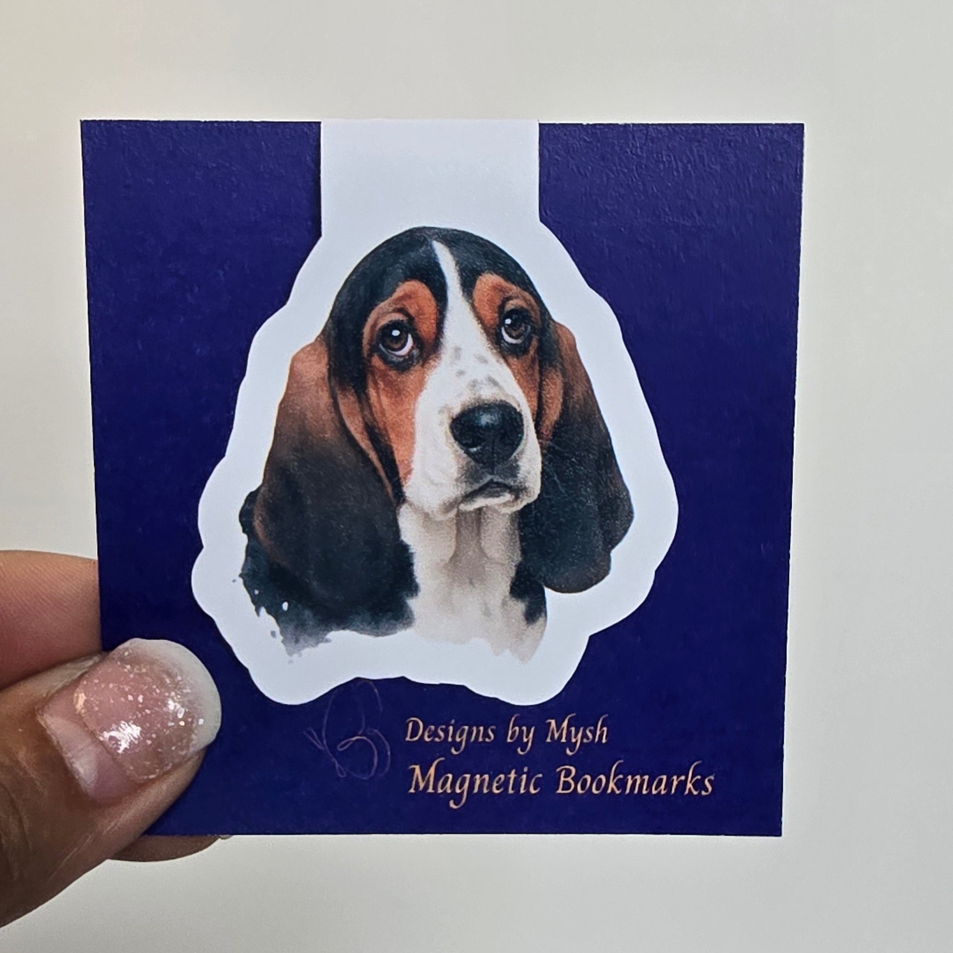 Magnetic bookmark with dog design held by a hand against a white background
