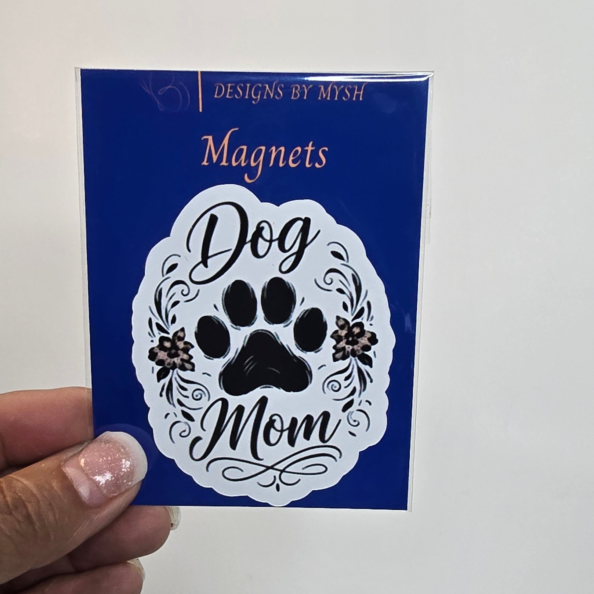 Card with 'Dog Mom' design held by a hand against a grid background