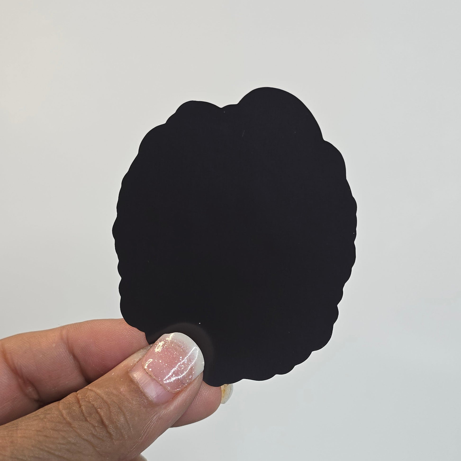 Hand holding a black, leaf-shaped object against a white background