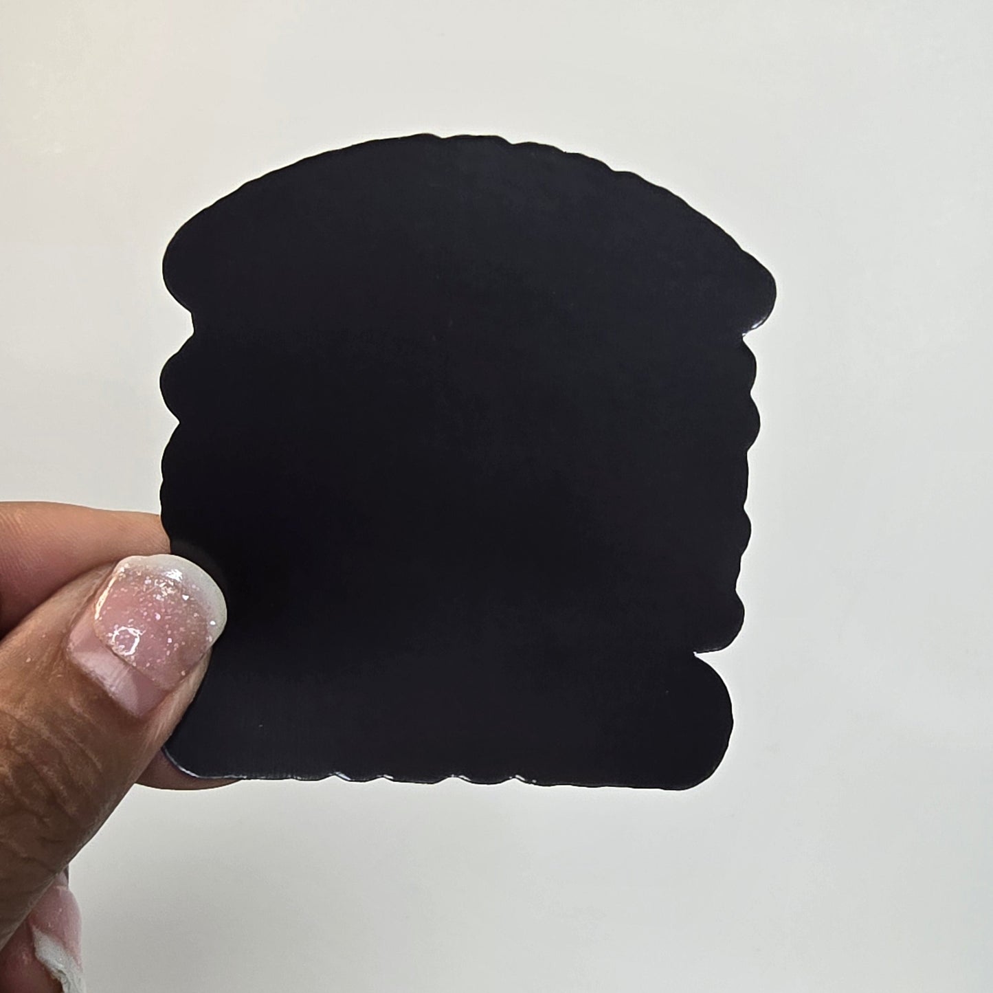 Black square object held by a hand with a white background