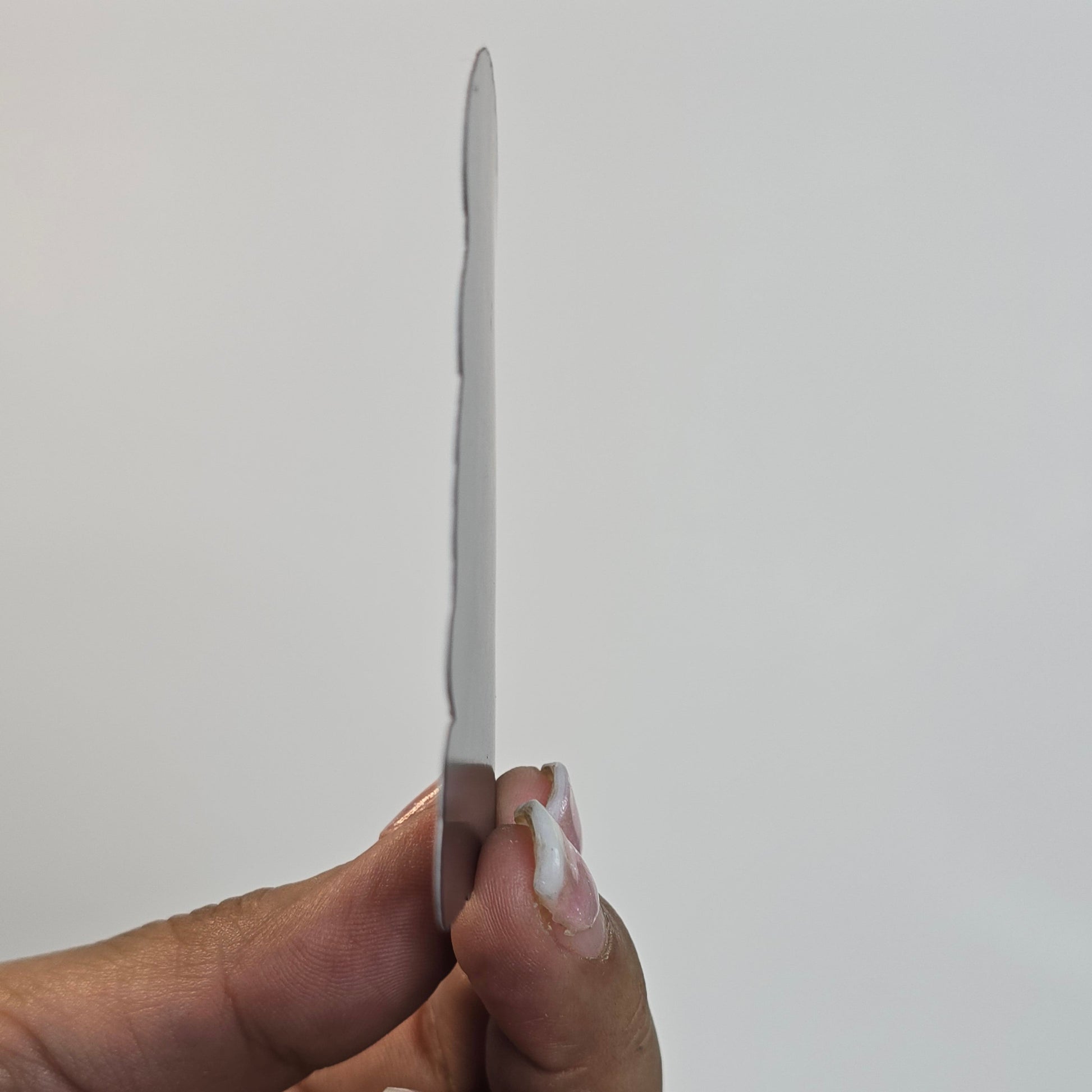 Hand holding a metal object against a plain background