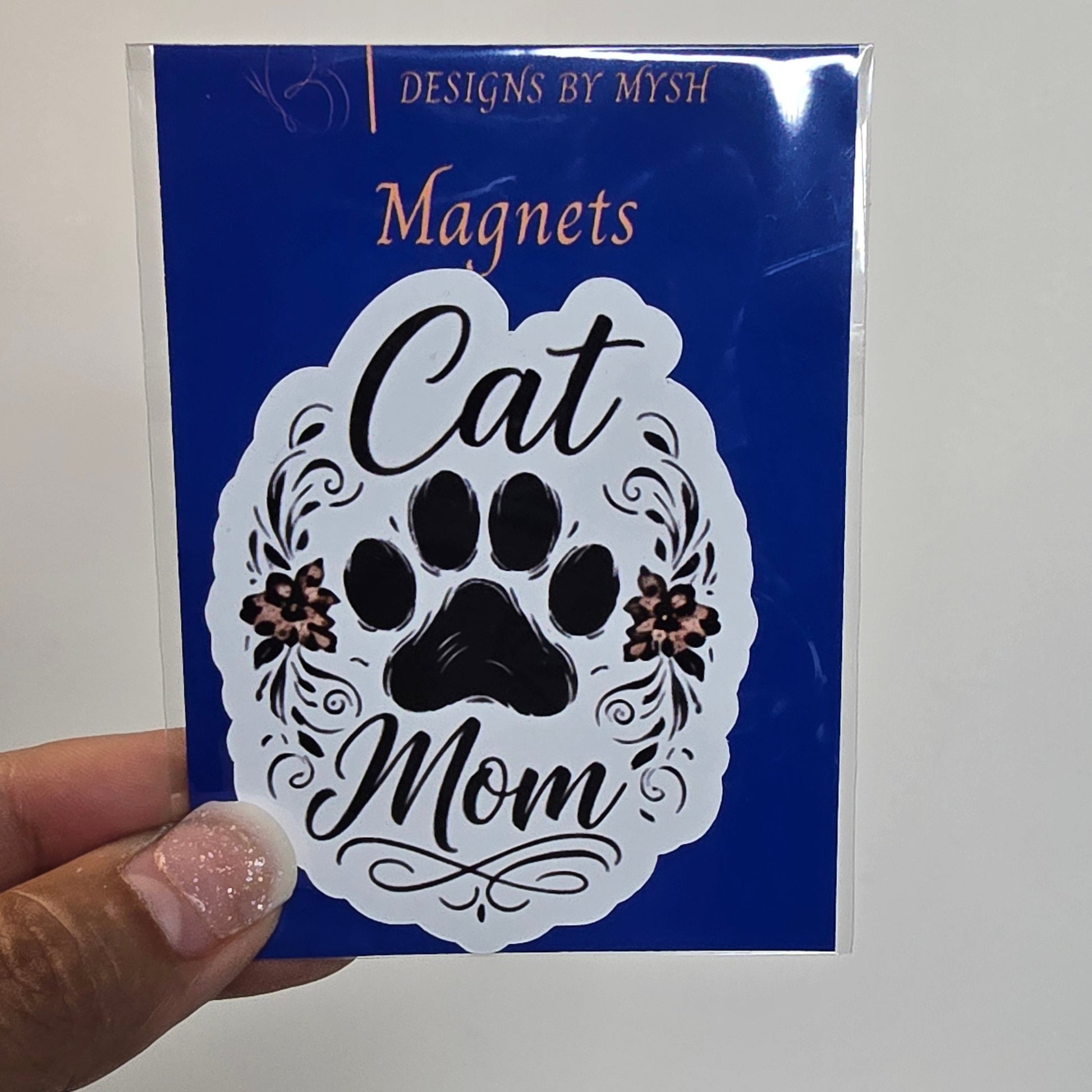 Card with 'Cat Mom' design held by a hand against a grid background