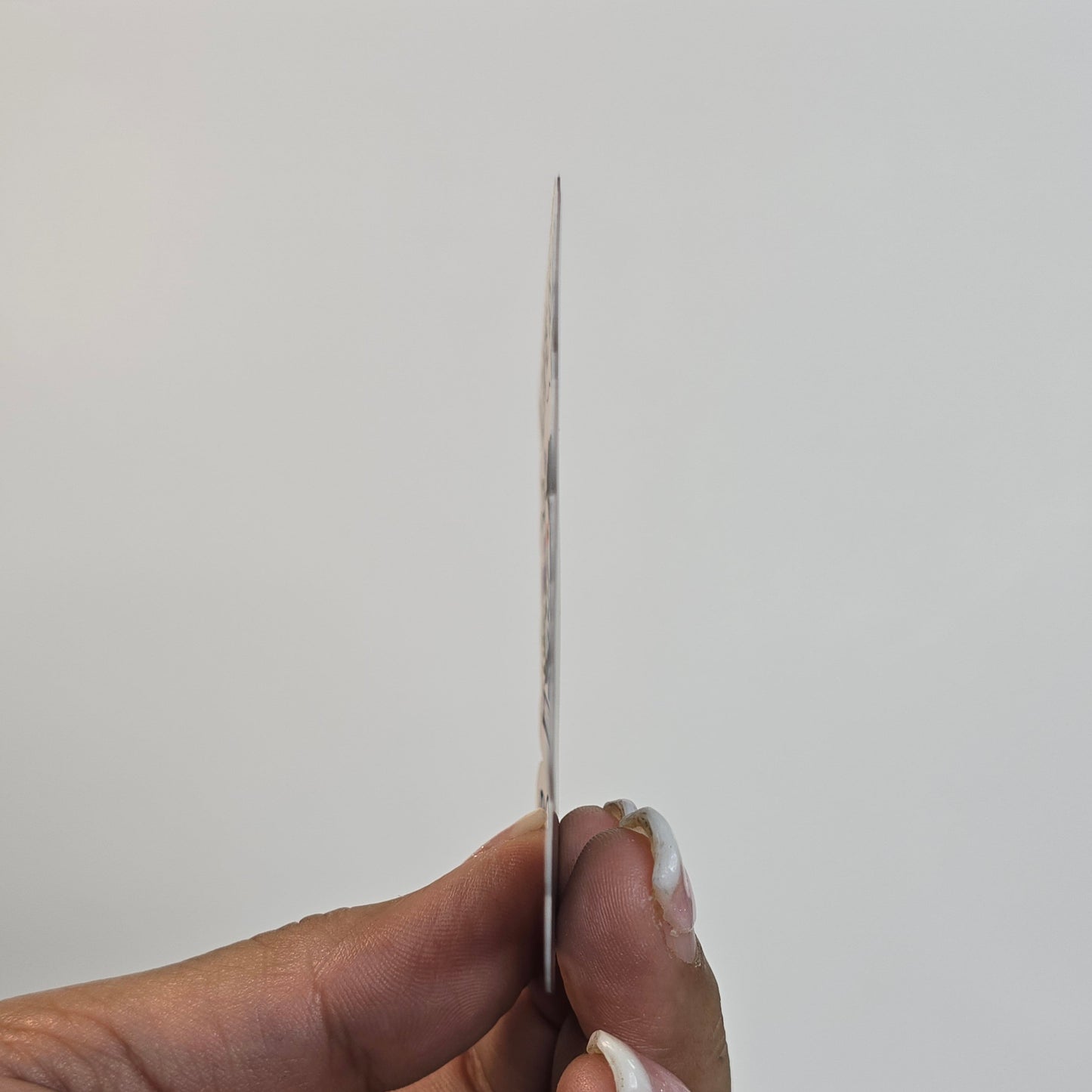 Hand holding a thin object against a plain background