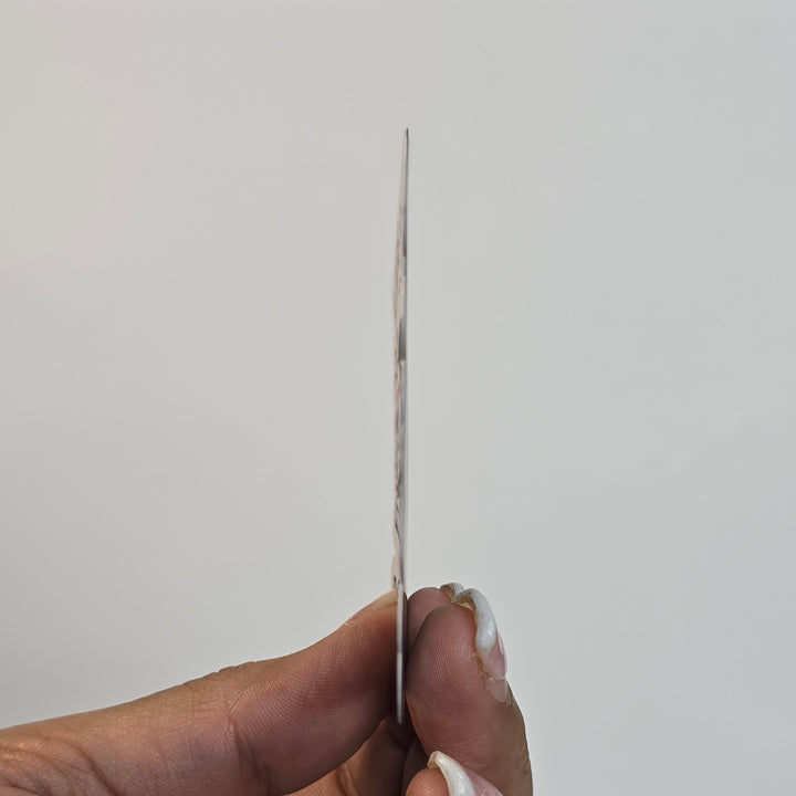 Hand holding a thin object against a plain background