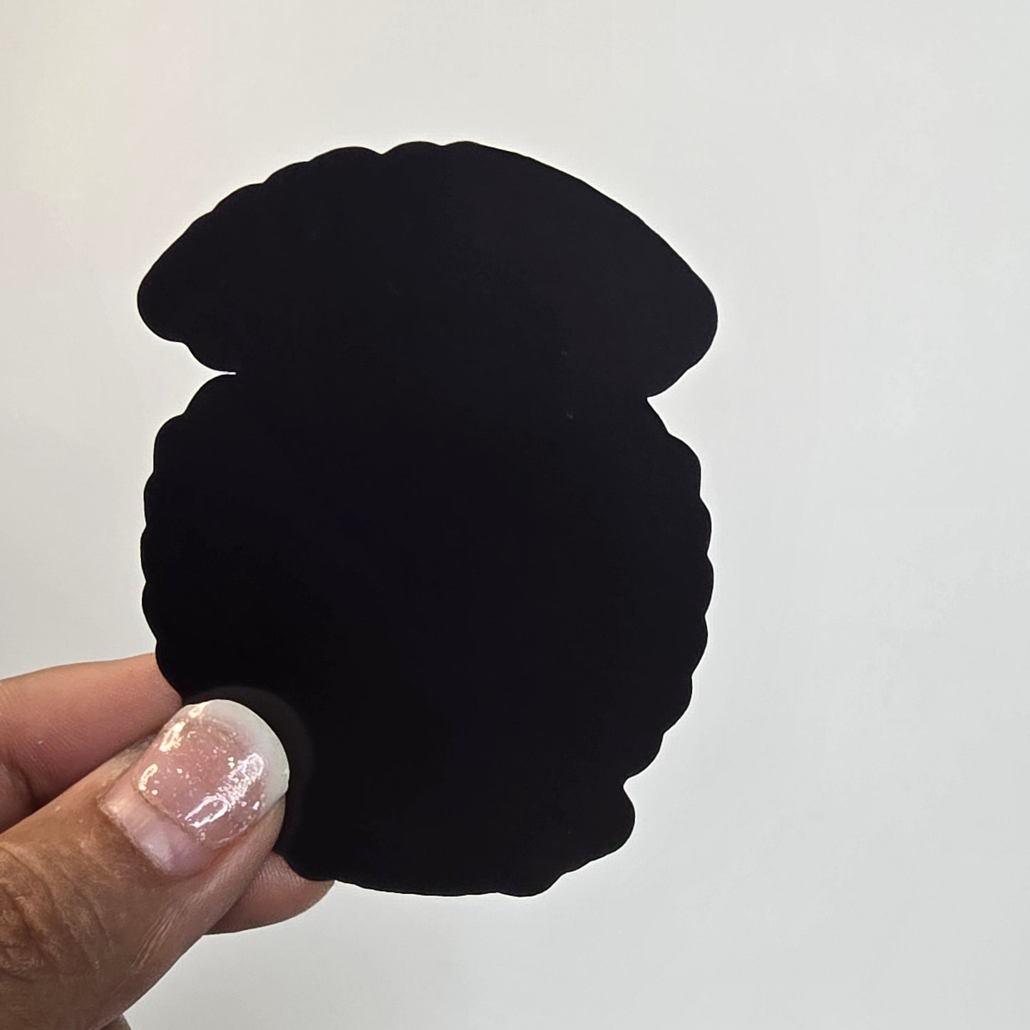 Black silicone cupcake-shaped product held by a hand against a white background