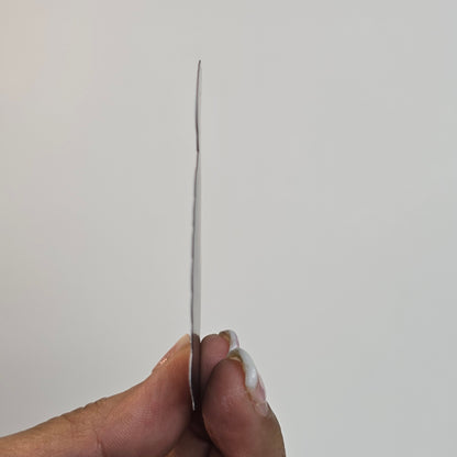 Hand holding a thin metal needle against a plain background