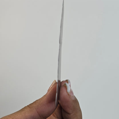 Hand holding a thin metal rod against a plain background