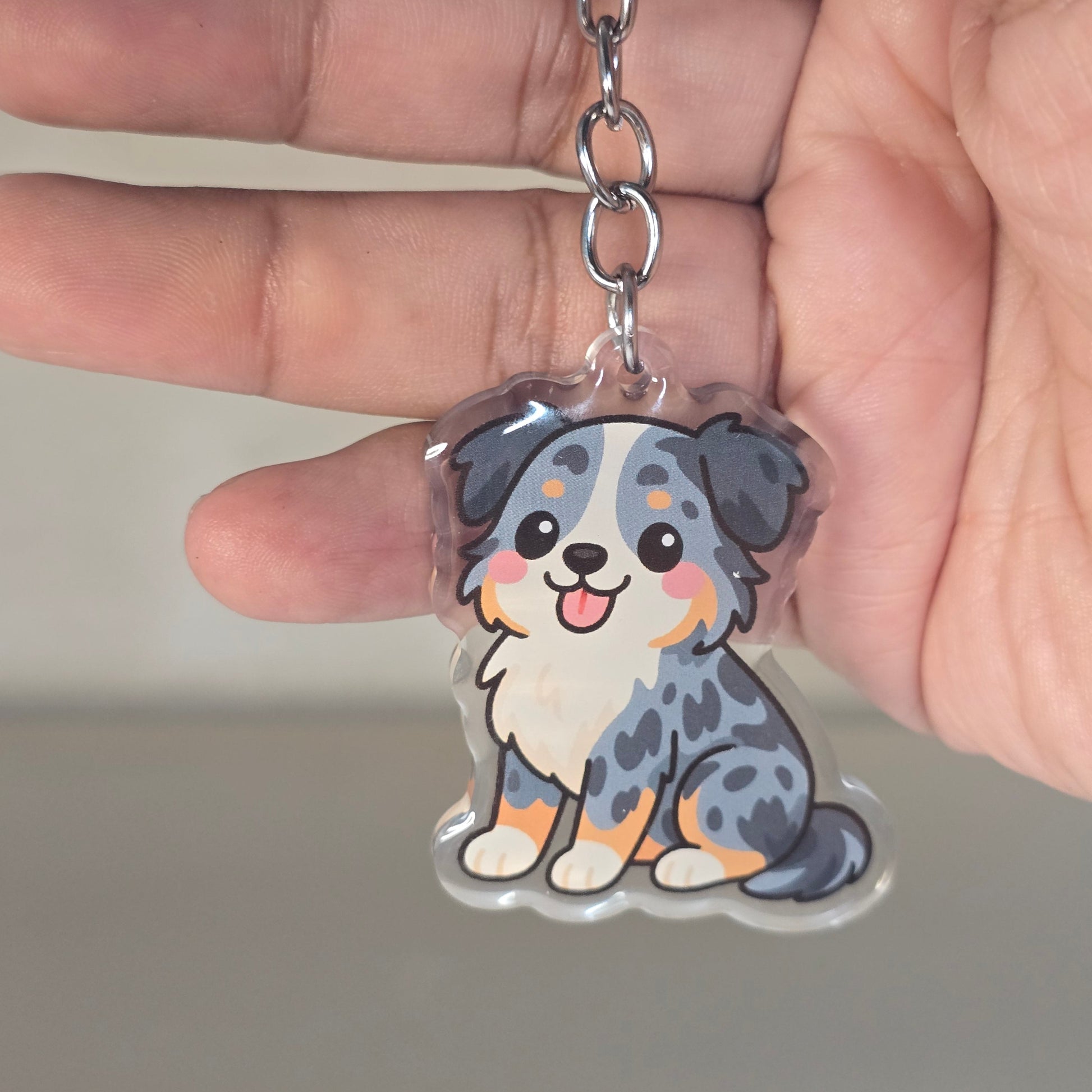 Hand holding a keychain with a cute animal design against a neutral background