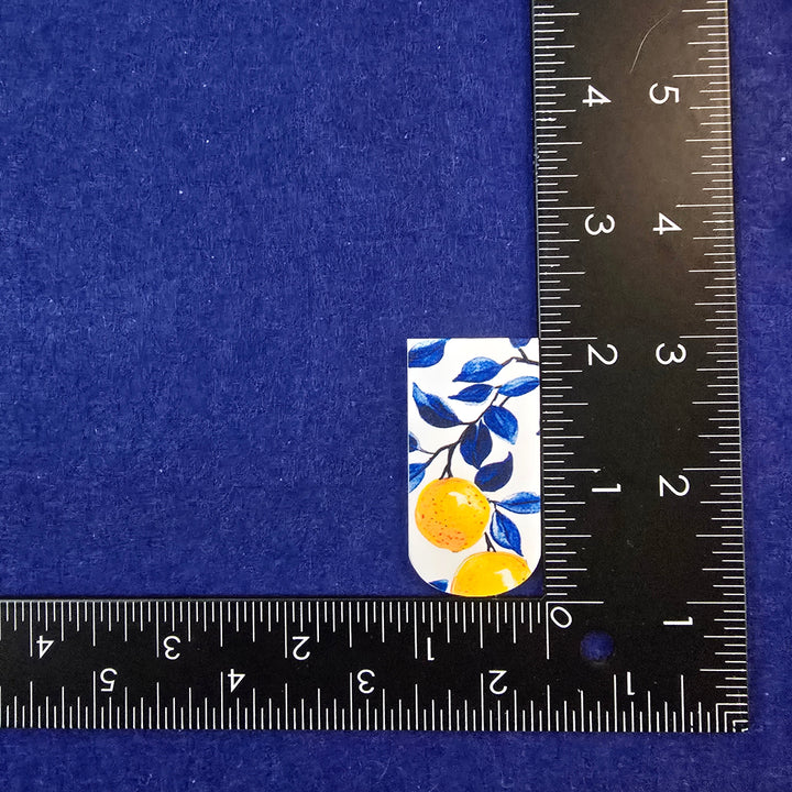 Small square sticker with floral design on a blue background, measured by a ruler.