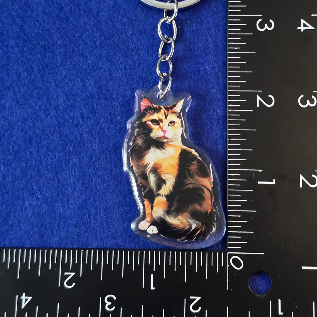 Keychain with a cat design on a blue surface with a ruler for scale.