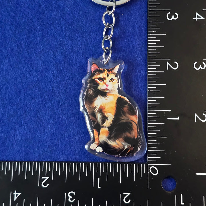 Keychain with a cat design on a blue surface with a ruler for scale.