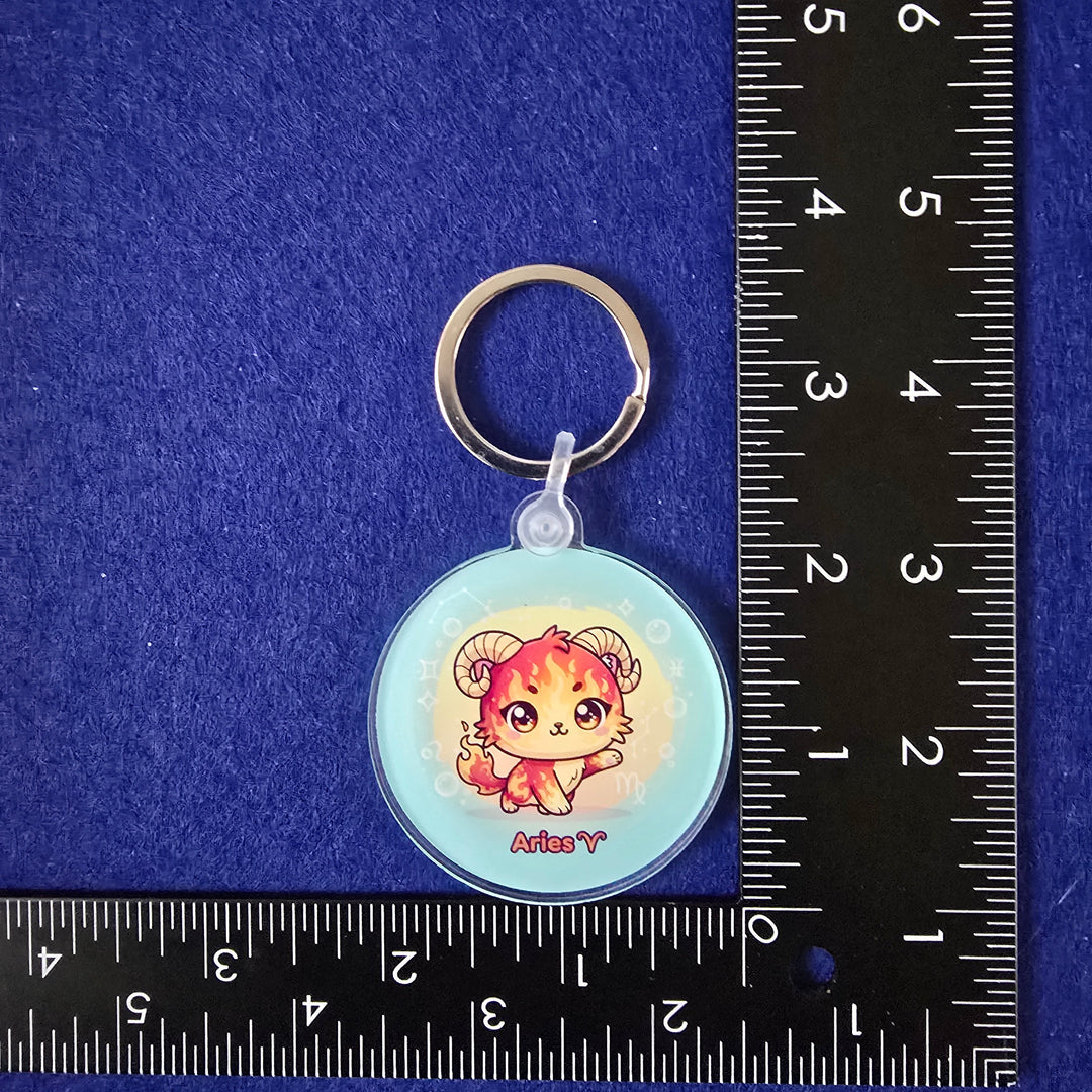 Keychain with a cartoon character on a blue surface with a ruler for scale.