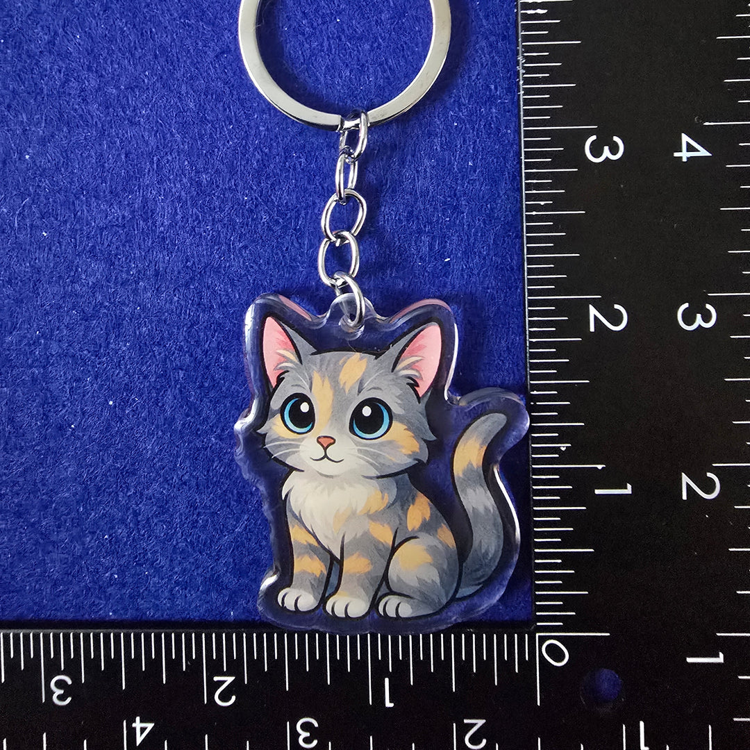 Keychain with a cat design on a blue surface with a ruler for scale.