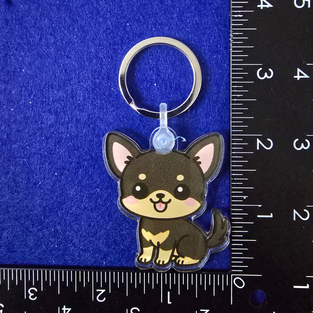 Dog-shaped keychain on a blue background with a ruler for scale