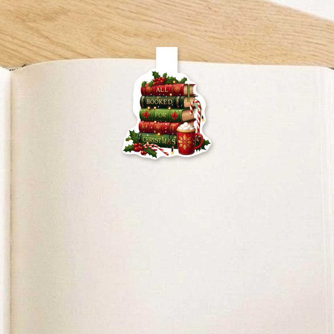 All Booked for Christmas book stack magnetic bookmark clipped over the top of an open book page – Designs by Mysh