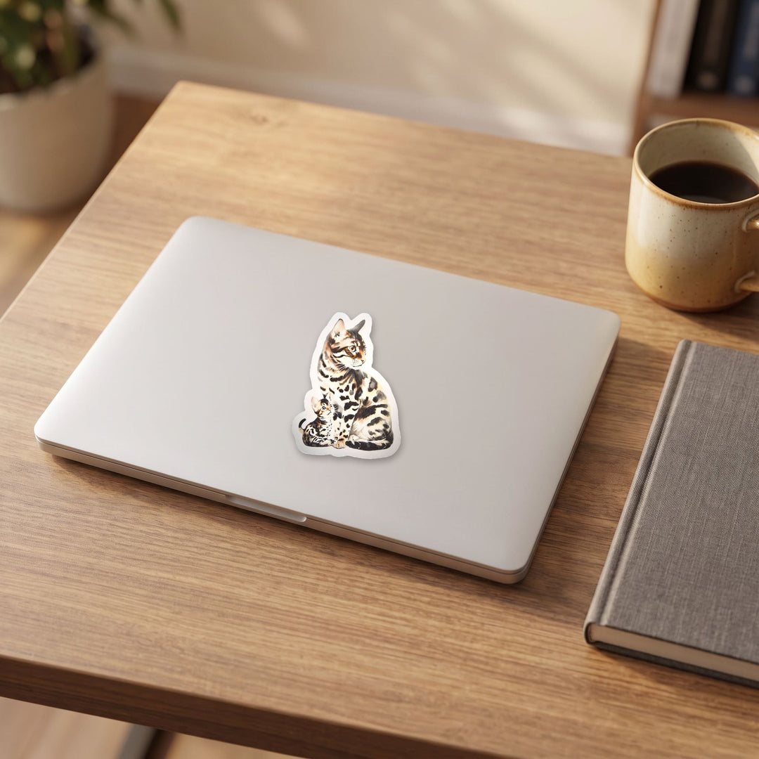 Bengal cat and kitten sticker on a laptop lid on a wooden desk